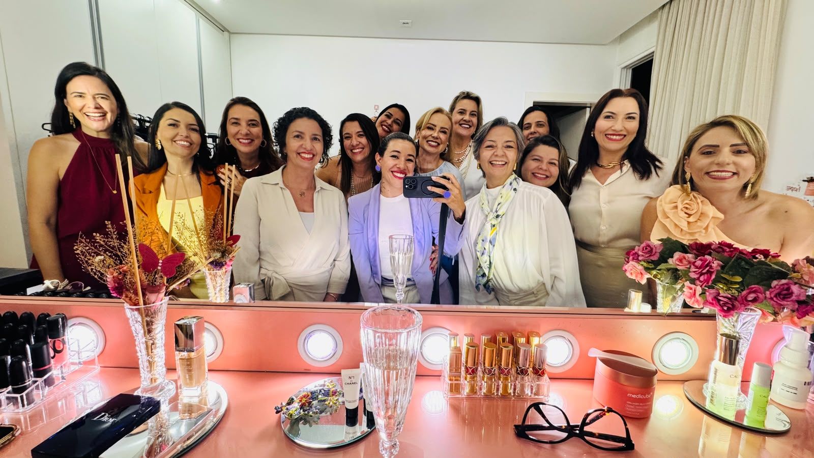 Grupo de empresárias reunidas diante de um espelho nos bastidores de um evento