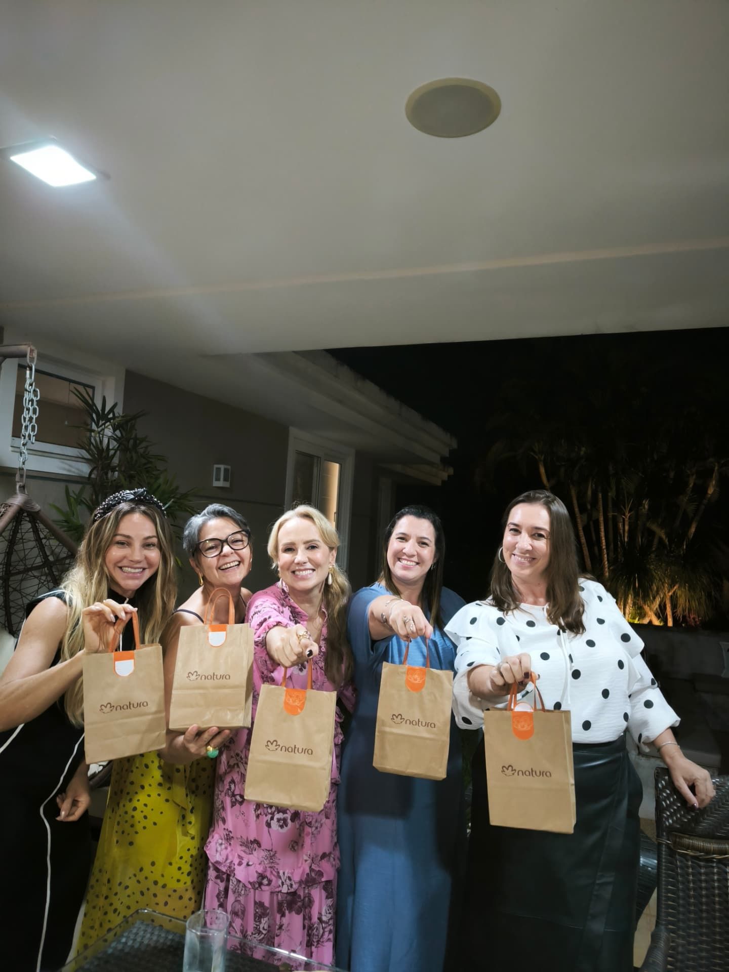 Cinco mulheres segurando sacolas de uma marca parceira em encontro da rede