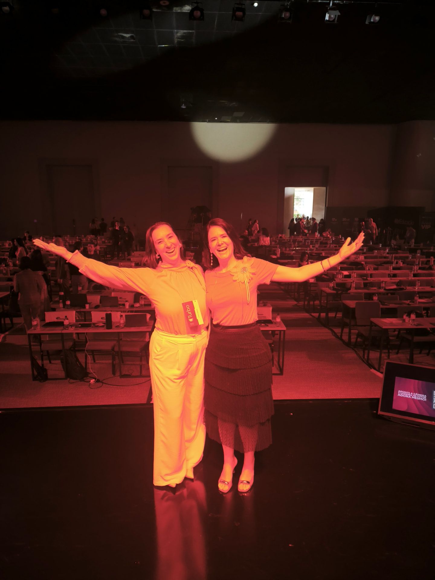 Duas fundadoras da Brasil por Elas de braços abertos em um palco