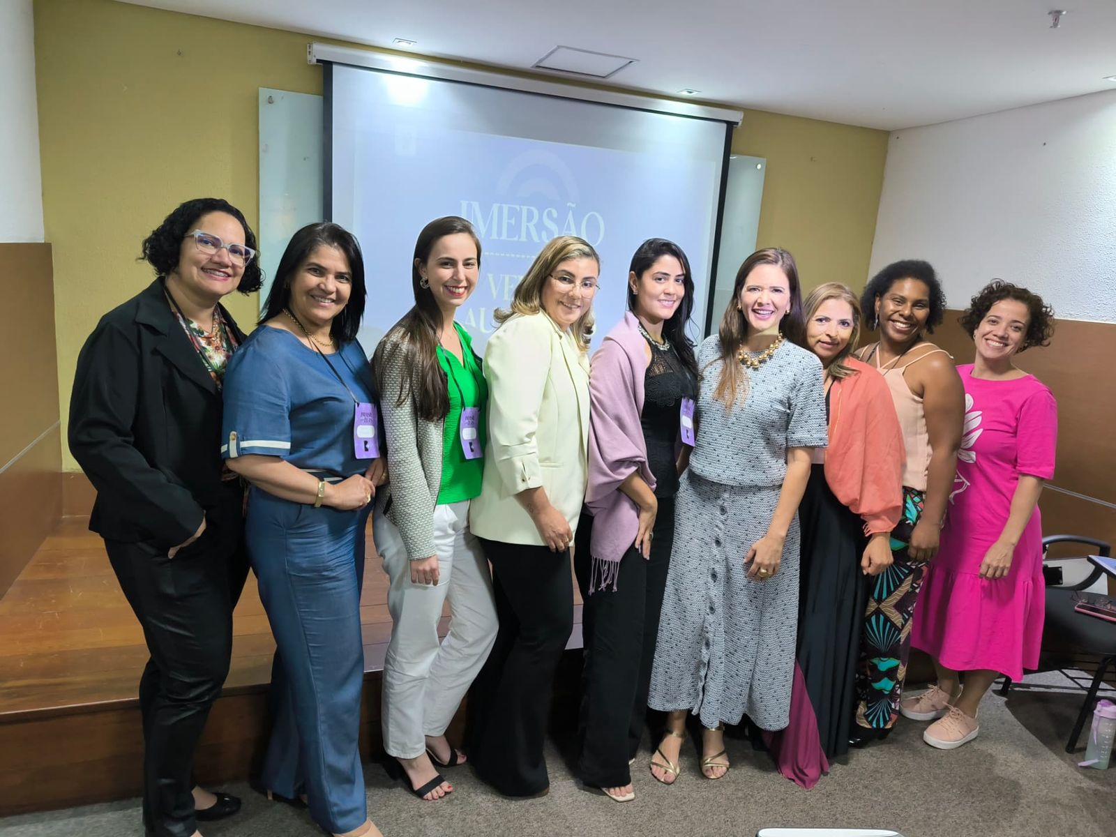 Participantes da imersão de vendas posando em frente ao telão do evento